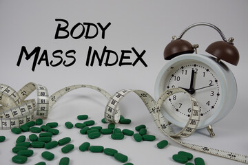 BMI Body Mass Index text with medicine, alarm clock and measuring tape on white background