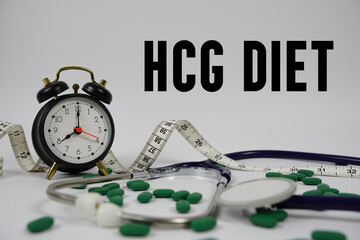 HCG Diet text with Stethoscope, medicine, measuring tape and alarm clock on white background