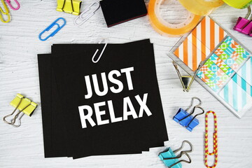 Just Relax text on stick note with stationery on concrete background