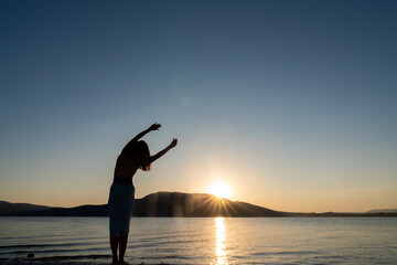 Silhouette of woman doing yoga and meditation exercises.
