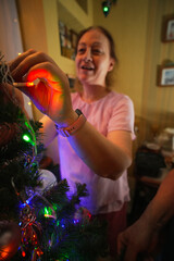 Woman decorates Christmas tree with ornaments in cozy living room during festive holiday season