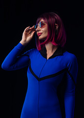 Stylish futuristic woman in blue bodysuit and sunglasses