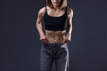 Woman suffering from anorexia on grey background, closeup