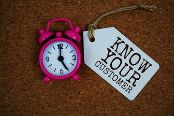 Know Your Customer text on price tag with alarm clock on cork board background