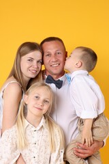 Fototapeta premium Family portrait of happy parents and their children on yellow background