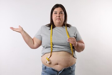 Overweight woman with measuring tape on white background
