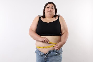 Overweight woman measuring her belly with tape on white background