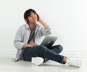 Student with headphones and laptop studying on floor indoors