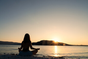 Silhouette of woman doing yoga and meditation exercises.