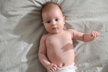 Cute newborn baby lying on bed, top view