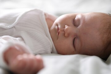 Cute newborn baby sleeping on bed, closeup