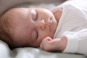 Cute newborn baby sleeping on bed, closeup