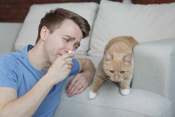 Man suffering from allergy with his cat at home