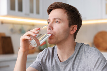 Man drinking water from glass in kitchen