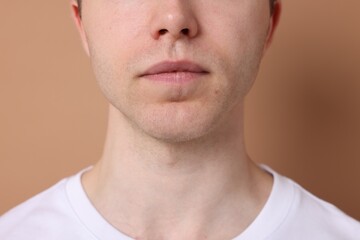Man after shaving on beige background, closeup