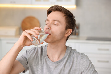 Man drinking water from glass in kitchen