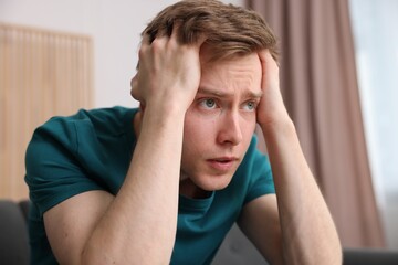 Scared man suffering from paranoia at home