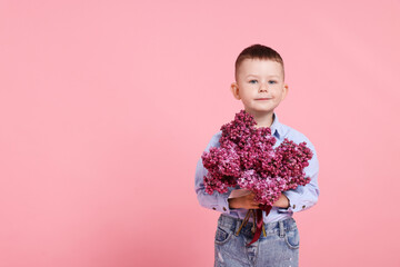 Little boy with bouquet of lilac flowers on pink background, space for text