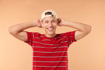 Naklejka premium Young man in stylish baseball hat on beige background