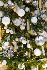 Decorated Christmas tree with Christmas balls, tinsel and warm yellow lights. Festive atmosphere.
