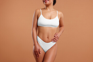 Obraz premium Woman in white underwear with smooth skin after epilation procedure on beige background, closeup