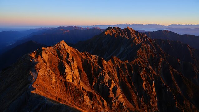 Rugged red mountains glowing under warm golden hour sunlight.