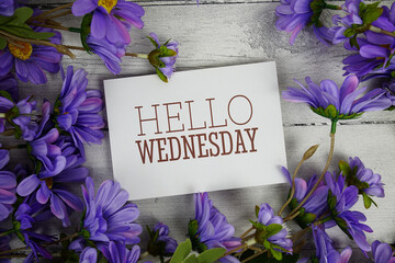 Hello Wednesday text with flowers decoration on wooden background