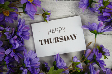 Happy Thursday text with flowers decoration on wooden background