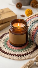 Warm and Cozy Home Decor Featuring a Lit Candle and Crochet Blanket on a White Surface