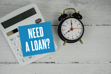Need a Loan text with calculator and alarm clock  on wooden background