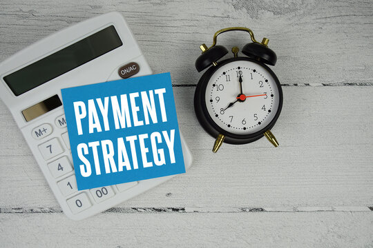 Payment Strategy text with calculator and alarm clock  on wooden background