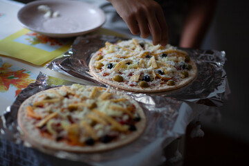 Fresh, just cooked pizza pizza with tomatoes, cheese and olives on a wooden table, at home in the...