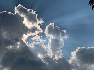 Sun Rays Beaming Through Clouds against Blue Sky. Dramatic Cloudscape © Christina Hab.