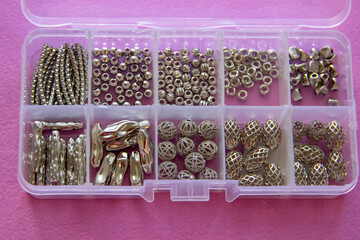 Furniture, beads for diy A clear box filled with various metallic beads and findings for jewelry...
