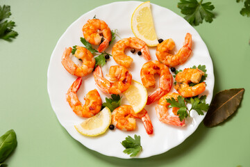Juicy fried shrimps with lemon slices in a plate isolated on green