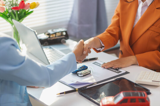 car dealer handing over keys female customer after successfully signing car sales contract. Concept of signing car sales contract and handing over keys so that customer can take car back immediately. - Powered by Adobe