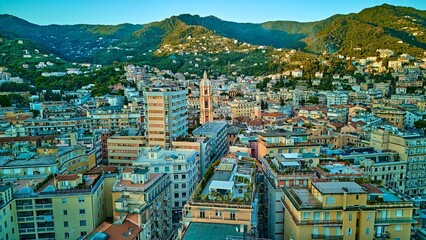 Wide aerial skyline of Rapallo city nestled between emerald Ligurian mountains and Mediterranean...