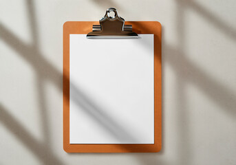 Blank Paper on Clipboard with Cast Sunlight Shadows on Wall
