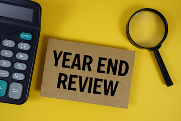 Year End Review text with magnifying glass anc calculator on yellow background