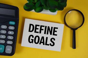 Define Goals text with magnifying glass anc calculator on yellow background