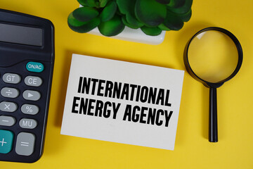 IEA International Energy Agency text with magnifying glass anc calculator on yellow background