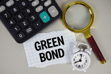 Green Bond text with alarm clock, magnifying glass anc calculator on gray background