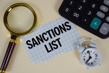 Sanctions List text with alarm clock, magnifying glass anc calculator on yellow background