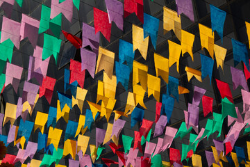 Bandeirolas festivas, coloridas, penduradas ao ar livre dançando ao vento com janelas desfocadas...