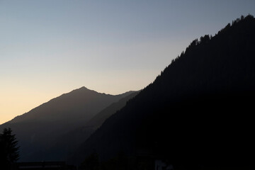 mountains of Montafon in Vorarlberg appear in soft layers of grey after the sunset in the golden hour