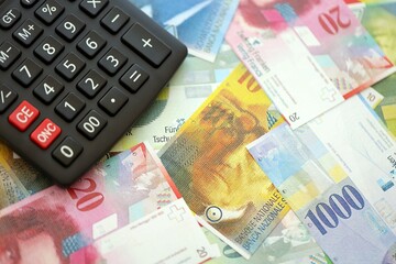 Swiss franc banknotes and calculator. The current francs money bills and calc lies on table
