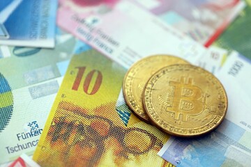 Swiss franc banknotes and bitcoin. The current francs money bills and bit coin lies on table