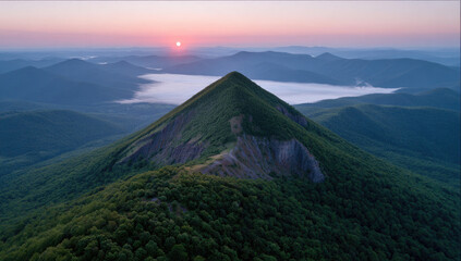 Majestic mountain peak at sunrise, surrounded by misty valley