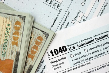 Hundred dollar bills and 1040 individual income tax return form blank close up