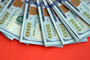 Big amount of United States hundred dollar bills on red background